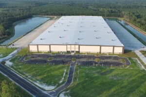Aerial view of Komar Distribution warehouse with parking lot and surrounding greenery