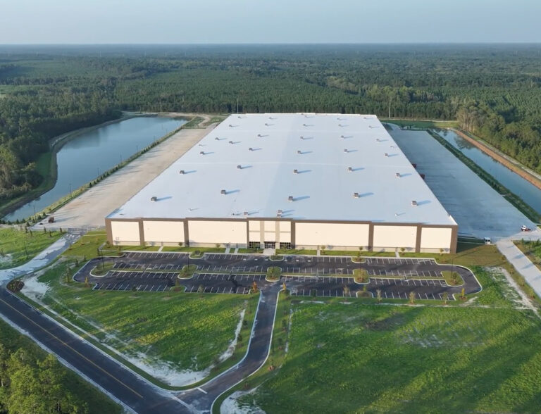 Aerial view of Komar Distribution warehouse with parking lot and surrounding greenery