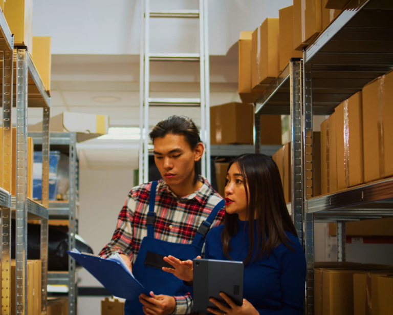 Warehouse workers with clipboard and tablet managing inventory for Komar Distribution.