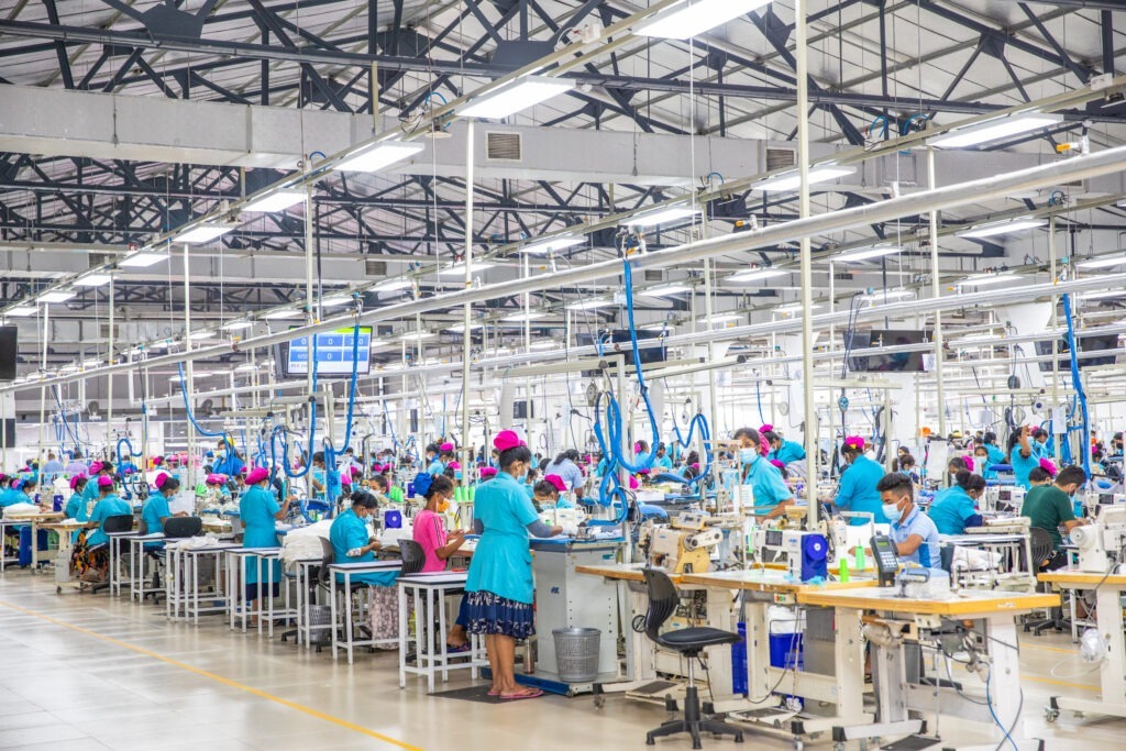 Garment factory workers on sewing machines in a bustling production line